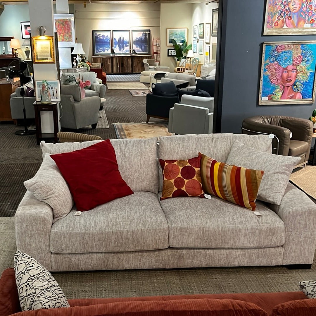 A parchment gray sofa adorned with warm and colorful pillows